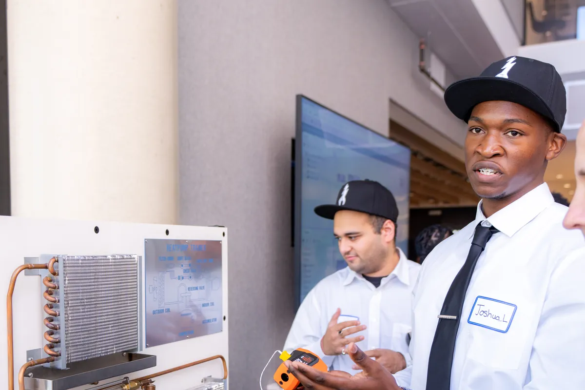 A trainee inspecting an HVAC unit during training.